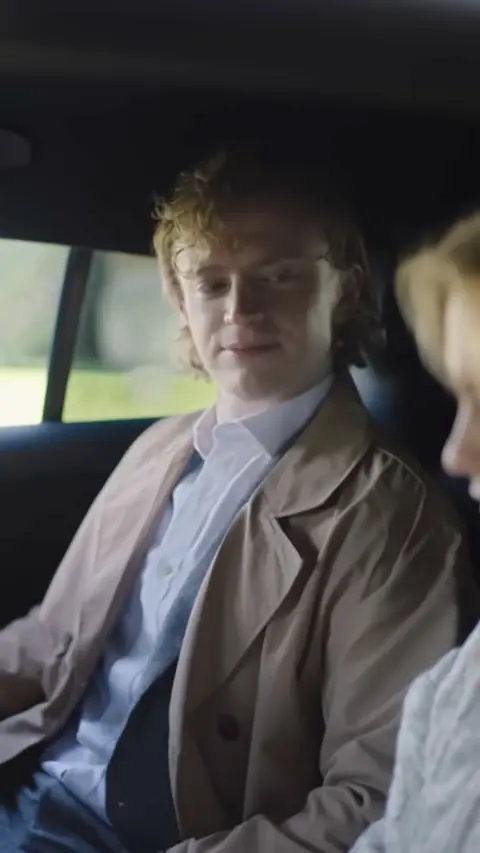 Beige trench coat over light blue shirt, in My Very Royal Romance
